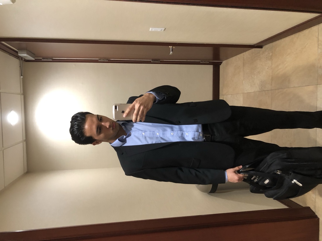 Nick in a suit with a laptop bag at his corporate job